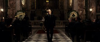 Movie still from “The Great Beauty” (2013), directed by Paolo Sorrentino – A man in a suit and tie standing in front of an altar; Wide shot, Low angle
