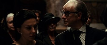 Movie still from “The Great Beauty” (2013), directed by Paolo Sorrentino – A group of people standing around each other in a room; Close Up shot, Over the shoulder angle