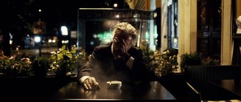 Movie still from “The Great Beauty” (2013), directed by Paolo Sorrentino – An older man sitting at a table in front of a cigarette; Medium shot, Over the shoulder angle