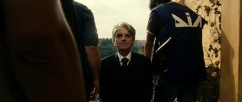 Movie still from “The Great Beauty” (2013), directed by Paolo Sorrentino – A man wearing a suit and tie standing next to two other men; Medium shot, Over the shoulder angle