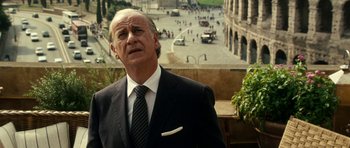 Movie still from “The Great Beauty” (2013), directed by Paolo Sorrentino – An older man wearing a suit and tie standing in front of a building; Close Up shot, Over the shoulder angle