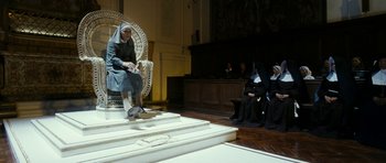 Movie still from “The Great Beauty” (2013), directed by Paolo Sorrentino – A woman sitting on a chair in a room with other people; Wide shot, Low angle