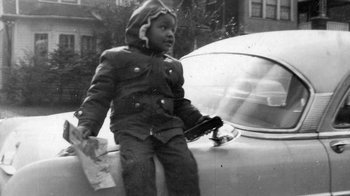 Movie still from “The Green Book: Guide to Freedom” (2019), directed by Yoruba Richen – A little boy is standing on the hood of a car; Medium shot, High angle