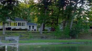 Movie still from “The Green Book: Guide to Freedom” (2019), directed by Yoruba Richen – A person sitting on a bench near a body of water; Extreme Wide shot, High angle