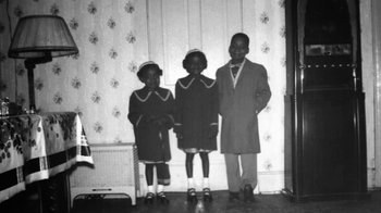 Movie still from “The Green Book: Guide to Freedom” (2019), directed by Yoruba Richen – A black and white photo of three children in dresses; Medium shot, High angle