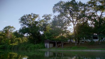 Movie still from “The Green Book: Guide to Freedom” (2019), directed by Yoruba Richen – A boat sits on the shore of a lake near trees; Extreme Wide shot, Low angle