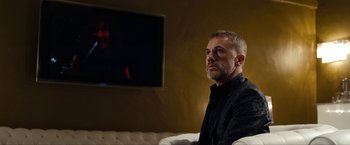 Movie still from “The Green Hornet” (2011), directed by Michel Gondry – A man sitting in front of a television in a room; Medium shot, Over the shoulder angle