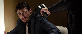 Movie still from “The Green Hornet” (2011), directed by Michel Gondry – A man in a suit holding a gun pointed at another man in a suit; Close Up shot, Over the shoulder angle