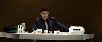 Movie still from “The Green Hornet” (2011), directed by Michel Gondry – A man sitting at a dinner table in front of an empty plate; Medium shot, Low angle