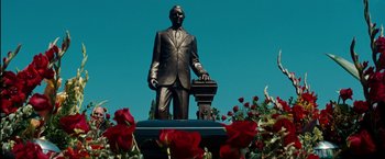 Movie still from “The Green Hornet” (2011), directed by Michel Gondry – A statue of a man standing in front of some red roses; Wide shot, Low angle