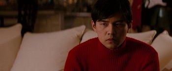 Movie still from “The Green Hornet” (2011), directed by Michel Gondry – A man sitting on a couch wearing a red sweater; Close Up shot, Over the shoulder angle