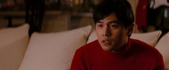 Movie still from “The Green Hornet” (2011), directed by Michel Gondry – A man sitting on a couch wearing a red sweater; Close Up shot, Over the shoulder angle