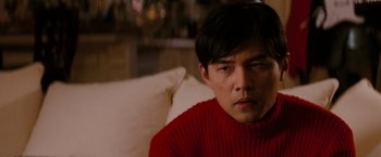 Movie still from “The Green Hornet” (2011), directed by Michel Gondry – A man sitting on a couch wearing a red sweater; Close Up shot, Over the shoulder angle