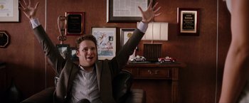 Movie still from “The Green Hornet” (2011), directed by Michel Gondry – A man sitting in a chair raising his hand; Medium shot, Low angle