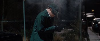 Movie still from “The Green Hornet” (2011), directed by Michel Gondry – A man in a green coat and a green hat is looking at his cell phone; Medium shot, Low angle