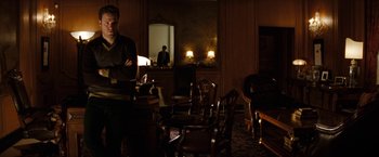 Movie still from “The Green Hornet” (2011), directed by Michel Gondry – A man standing in front of a table in a dark room; Medium shot, Over the shoulder angle