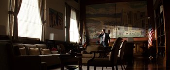 Movie still from “The Green Hornet” (2011), directed by Michel Gondry – A man standing in a living room talking on a phone; Wide shot, Low angle