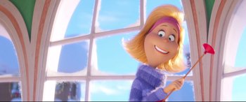 Movie still from “The Grinch” (2018), directed by Yarrow Cheney – A woman with blonde hair is smiling in front of a window; Close Up shot, Low angle