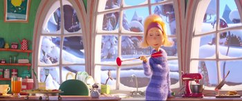Movie still from “The Grinch” (2018), directed by Yarrow Cheney – A woman is holding a red object in a kitchen; Medium shot, Over the shoulder angle