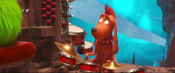 Movie still from “The Grinch” (2018), directed by Yarrow Cheney – A dog is playing the drums in a cartoon; Medium shot, Over the shoulder angle