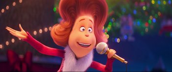 Movie still from “The Grinch” (2018), directed by Yarrow Cheney – A woman is holding a microphone in her hand; Close Up shot, Low angle