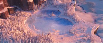 Movie still from “The Grinch” (2018), directed by Yarrow Cheney – An aerial view of a frozen lake surrounded by snow covered trees; Extreme Wide shot, High angle
