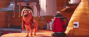 Movie still from “The Grinch” (2018), directed by Yarrow Cheney – A dog with a hat on standing next to an electric tea kettle; Medium shot, Over the shoulder angle