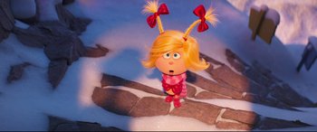 Movie still from “The Grinch” (2018), directed by Yarrow Cheney – A doll with red bows is standing in the snow; Medium shot, Over the shoulder angle