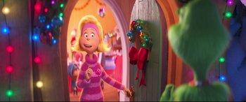Movie still from “The Grinch” (2018), directed by Yarrow Cheney – A woman is standing in front of a door with a wreath on it; Medium shot, Over the shoulder angle
