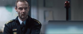 A man in a uniform sitting in front of a laptop