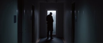 A man standing in front of an open door in a dark room