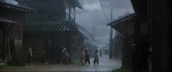 Movie still from “The Handmaiden” (2016), directed by Park Chan-wook – A group of people walking down a street in the rain; Extreme Wide shot, High angle