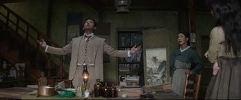 Movie still from “The Handmaiden” (2016), directed by Park Chan-wook – A man standing in front of a table with a painting; Medium shot, Low angle