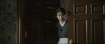 Movie still from “The Handmaiden” (2016), directed by Park Chan-wook – A young woman standing in front of an open door; Medium shot, Over the shoulder angle
