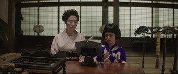 Movie still from “The Handmaiden” (2016), directed by Park Chan-wook – A woman sitting next to a young girl reading a book; Medium shot, Low angle