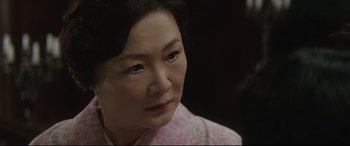Movie still from “The Handmaiden” (2016), directed by Park Chan-wook – An older woman looking at the camera while wearing a pink shirt; Close Up shot, Over the shoulder angle