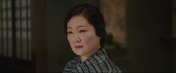 Movie still from “The Handmaiden” (2016), directed by Park Chan-wook – An older asian woman wearing a black and white striped shirt; Close Up shot, Low angle