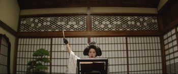 Movie still from “The Handmaiden” (2016), directed by Park Chan-wook – A woman wearing a black hat and holding a stick; Medium shot, Low angle
