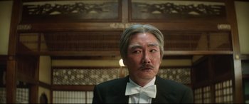Movie still from “The Handmaiden” (2016), directed by Park Chan-wook – A man in a suit and a bow tie in a room; Close Up shot, Low angle