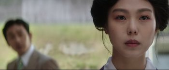 Movie still from “The Handmaiden” (2016), directed by Park Chan-wook – A young girl's face with grass in the background; Close Up shot, Over the shoulder angle