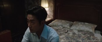 A man sitting on a bed in front of a pile of money