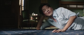 Movie still from “The Handmaiden” (2016), directed by Park Chan-wook – A man laying on the ground in a living room; Medium shot, Low angle