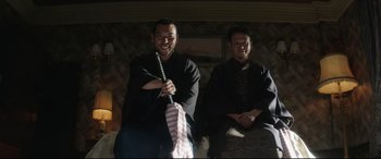 Movie still from “The Handmaiden” (2016), directed by Park Chan-wook – Two men sitting on a couch in front of a fire place; Medium shot, Low angle