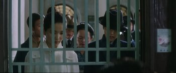 Movie still from “The Handmaiden” (2016), directed by Park Chan-wook – A group of people standing next to each other behind a fence; Medium shot, Over the shoulder angle