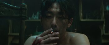 Movie still from “The Handmaiden” (2016), directed by Park Chan-wook – A man smoking a cigarette with blood on his hand; Close Up shot, Low angle