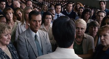 Movie still from “The Happening” (2008), directed by M. Night Shyamalan – A group of people standing in a room; Medium shot, Over the shoulder angle