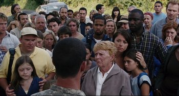 Movie still from “The Happening” (2008), directed by M. Night Shyamalan – A group of people standing around a crowd of people; Medium shot, Over the shoulder angle