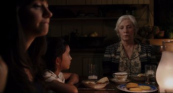 Movie still from “The Happening” (2008), directed by M. Night Shyamalan – A group of people sitting at a table with plates of food; Medium shot, Over the shoulder angle