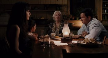 Movie still from “The Happening” (2008), directed by M. Night Shyamalan – An older woman sitting at a dinner table with family; Medium shot, Over the shoulder angle