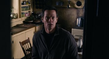 Movie still from “The Happening” (2008), directed by M. Night Shyamalan – A man standing in a kitchen wearing a black shirt; Close Up shot, High angle